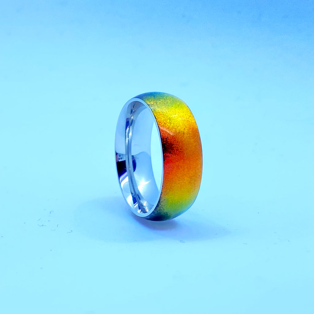 Stainless steel ring with red iridescent flip inlay on white background